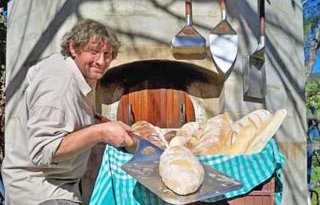 Pete holding a pizza peel with a freshly baked loaf on the peel